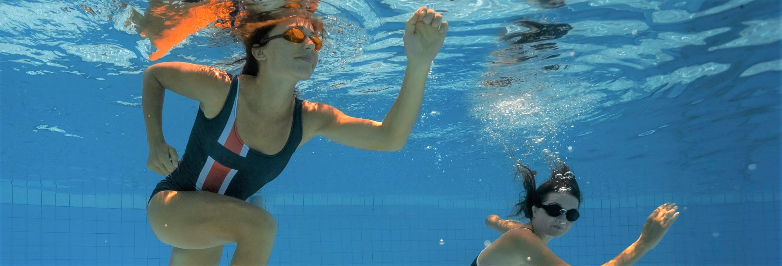 Women,Under,Water,Runs,Along,The,Bottom,Of,A,Swimming